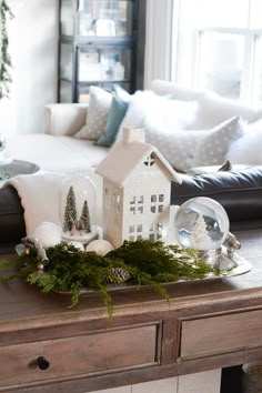 a living room decorated for christmas with white and green decorations on the coffee table in front of the couch