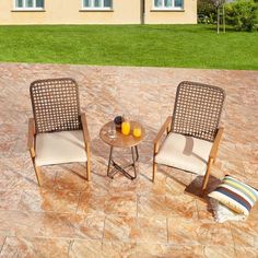 two chairs sitting on top of a patio next to a table with an orange juice