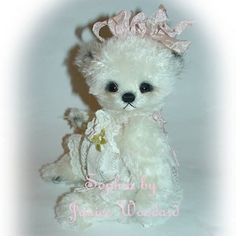 a white teddy bear with a pink crown on it's head sitting in front of a white background