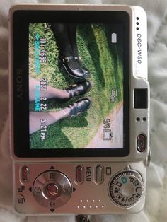 a cell phone sitting on top of a white bed next to a pair of shoes