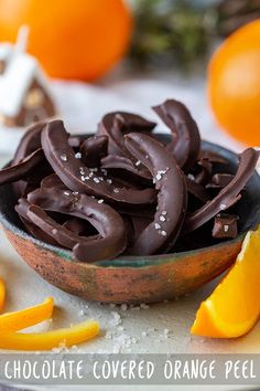 chocolate covered orange peels in a bowl on a table next to an orange slice