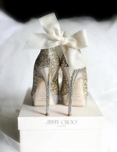 a pair of glittered high heels with a white bow on the top are sitting on a box