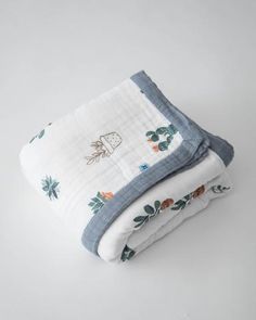 two blankets folded on top of each other in front of a white background with blue trim