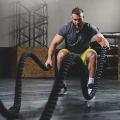 a man is doing battle ropes in the gym