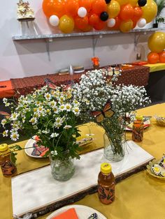 the table is set with orange, yellow and white balloons in the shape of butterflies