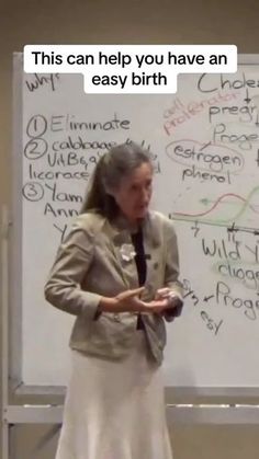 a woman standing in front of a whiteboard with writing on it