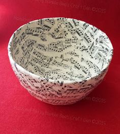 a white and black bowl with musical notes in it on a red tablecloth background