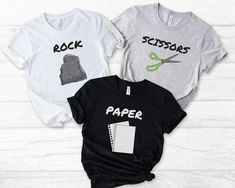 Looking for a fun, easy, and creative group Halloween costume? Our Rock Paper Scissors shirts are the perfect trio costume idea for friends or family! Each shirt features one of the classic game icons: rock, paper, or scissors. Whether you're heading to a Halloween party or just want a low-effort costume with a big impact, these matching tees are sure to win laughs and compliments. No need for complicated costumes, these shirts are made with a soft cotton and a quality print that will have you f Trio Matching Shirts, Scissors Costume, Rock Paper Scissors Costume, Group Halloween Shirts, Halloween Shirts Funny, Family Halloween Shirts, Costume Simple, Trio Costumes, Friend Costumes