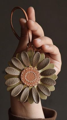 a hand holding a key chain with a flower on it