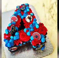 a decorated letter shaped cake sitting on top of a doily covered table with red, white and blue flowers