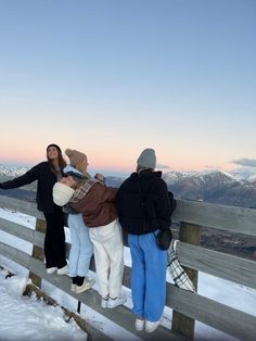 three people standing on a wooden fence in the snow