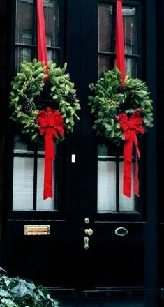 two christmas wreaths on the front door of a house