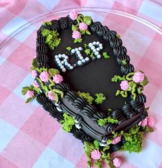 a heart shaped cake with flowers and letters on it sitting on a checkered tablecloth