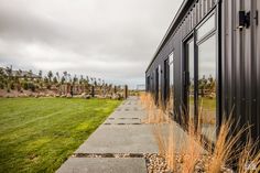 a black building sitting on top of a grass covered field next to a lush green field