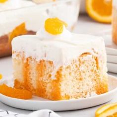 a slice of cake on a white plate with oranges around it and the rest of the cake in the background