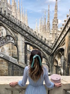 a woman in a blue dress is looking at the cathedral