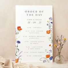 an order of the day card next to a vase with wildflowers in it