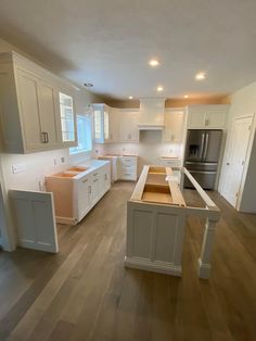 an empty kitchen with white cabinets and wood floors