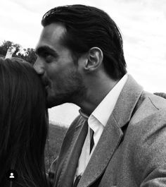 a man in a suit and tie kissing a woman