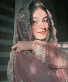 a woman in a pink dress with a veil on her head is posing for the camera