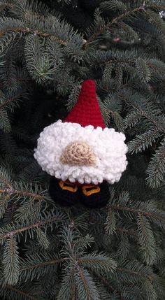 a crocheted gnome ornament hanging from a pine tree in front of some needles