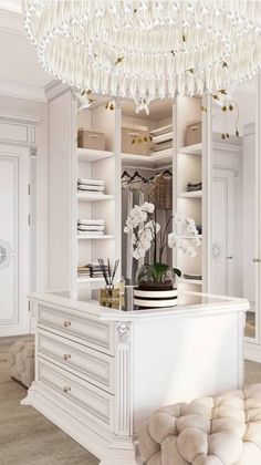 a room with white furniture and a chandelier hanging from it's ceiling