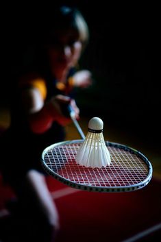 a badminton racket with two white shuttles on it and a woman in the background