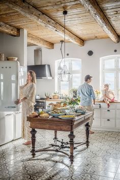 a man and woman standing in a kitchen next to a table with food on it