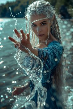 a woman with long hair and braids standing in the water holding her hands out