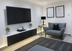 a living room with a couch, chair and flat screen tv mounted on the wall