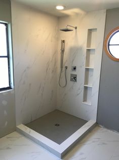 a bathroom with a walk in shower and built in shelves on the wall next to it