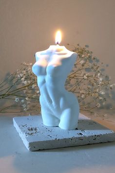 a white candle sitting on top of a stone block