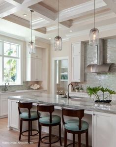 a large kitchen with white cabinets and wood flooring on the walls, along with two bar stools