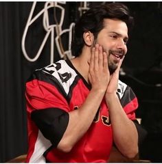 a man with his hands in the air while wearing a red and black football jersey