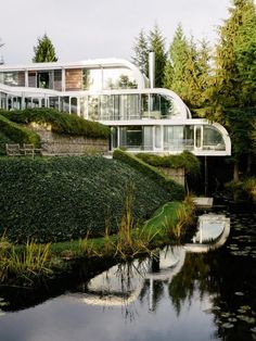 a house on the side of a hill with water running through it and grass growing all around