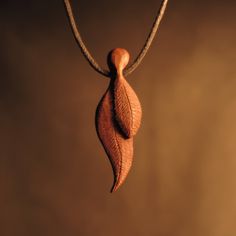 a wooden leaf is hanging from a cord on a brown background with some light coming through it