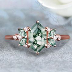 an engagement ring with green and white stones on the front, set in rose gold