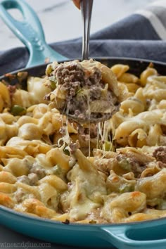 a blue casserole dish with meat and cheese being lifted by a spatula