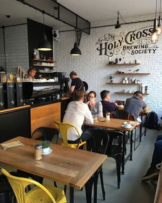 people sitting at tables in a restaurant with yellow chairs and wooden tables, while others are eating