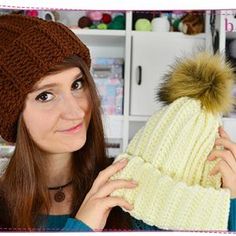 a woman is holding up a knitted hat with a pom - pom