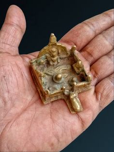 a hand holding a small bronze object in it's palm