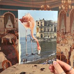 a person holding up an image of a flamingo in the middle of a restaurant