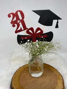 a vase filled with flowers sitting on top of a wooden stump next to a graduation hat