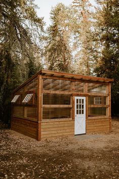 a small wooden building with a white door and windows in the middle of a forest