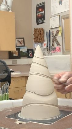 a person is making a sculpture in the shape of a cone on top of a table