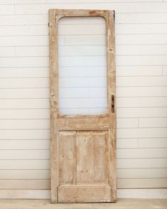 an old wooden door sitting in front of a white wall with a window on it