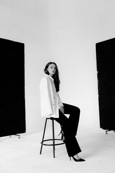 a woman sitting on top of a stool in front of black and white photo booths