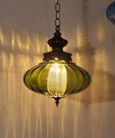 a green glass light hanging from a ceiling