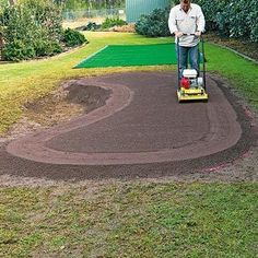 a man using a lawn mower in the middle of a yard with green grass