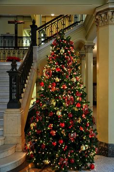 a decorated christmas tree in the middle of a building with stairs and balconies